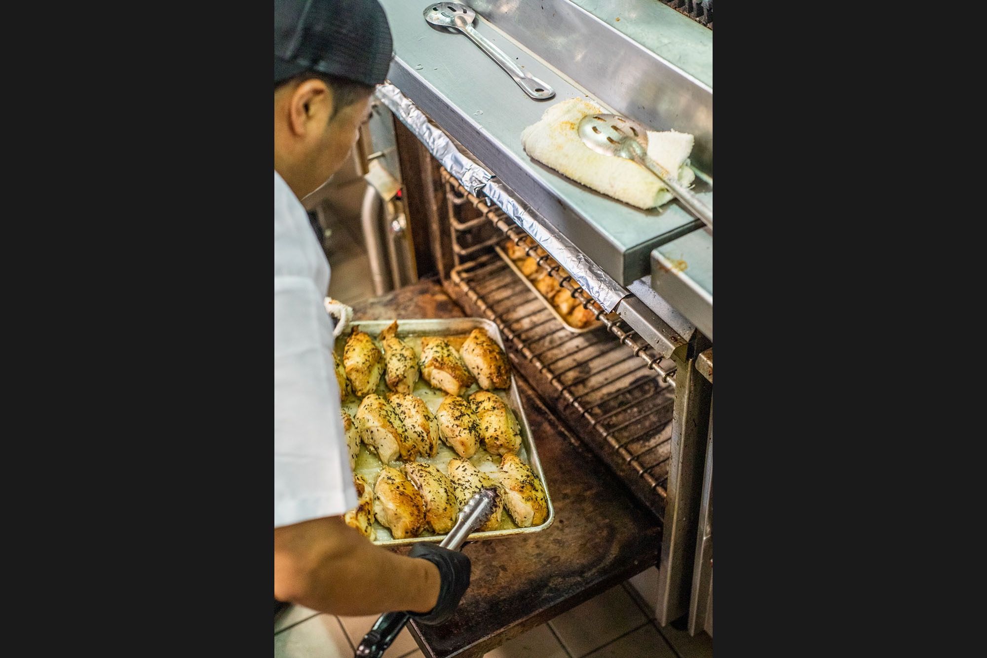 A chef loading a pan of chicken into the oven at Mulberry & Vine.