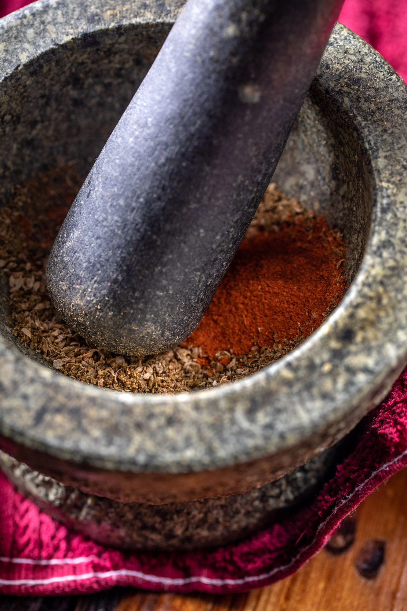 A mortar and pestel grinding up spices to go into an Indian recipe.