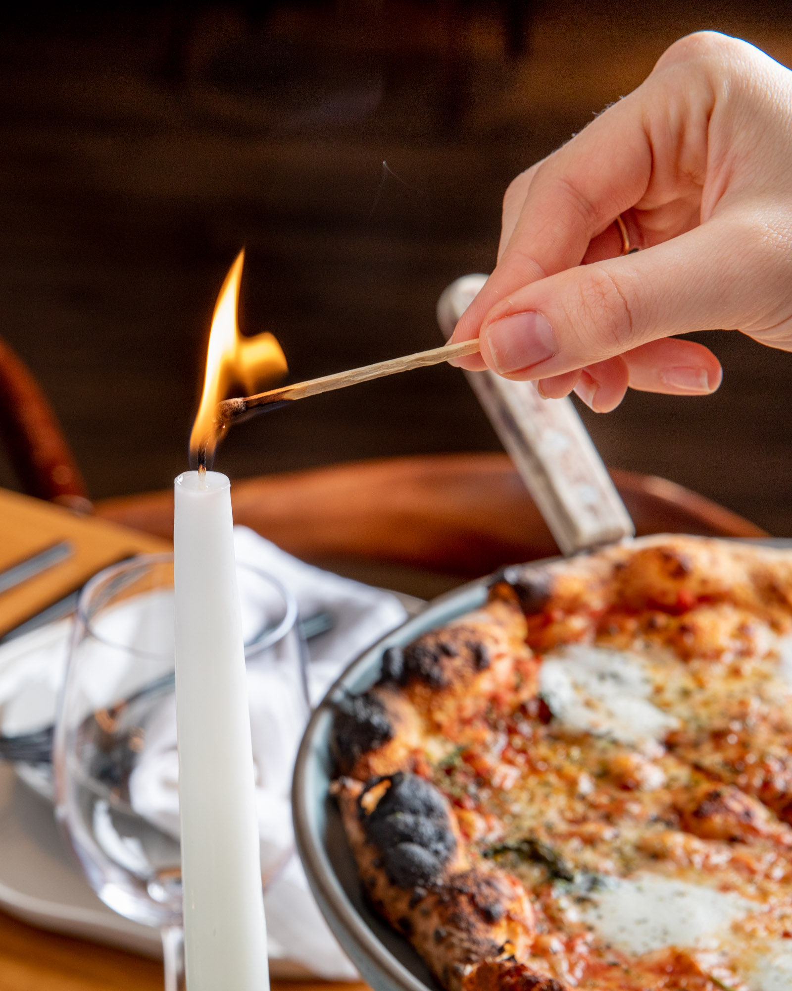 A candle being lit next to a romantic pizza